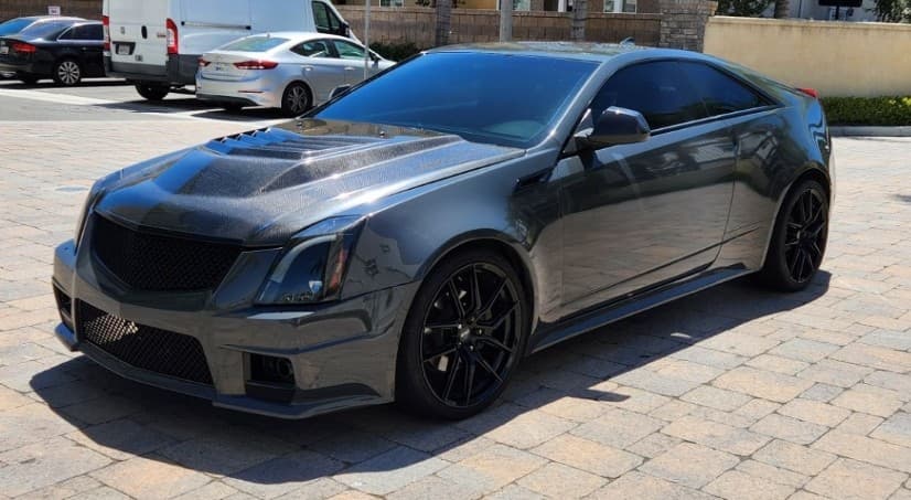 Front three-quarter view of the gray 2011 Cadillac CTS Coupe project car with black wheels and a vented hood